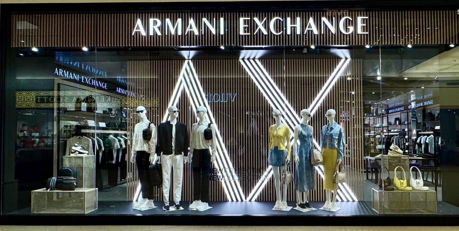 Armani Exchange storefront window with illuminated AX logo and styled mannequins